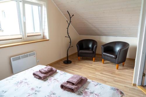 1 dormitorio con 2 sillas negras y 1 cama en Cosy Family Guesthouse with Sauna and Garden en Kuressaare