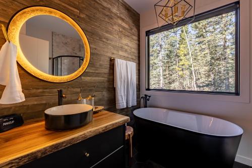 a bathroom with a tub and a large mirror at New Modern Rustic A-Frame Cabin with Barrel Sauna in Nordegg
