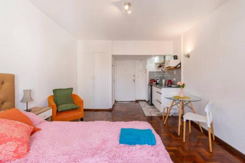 1 dormitorio con cama rosa y cocina en Disfruta Recoleta desde este tranquilo Monoambiente en Buenos Aires