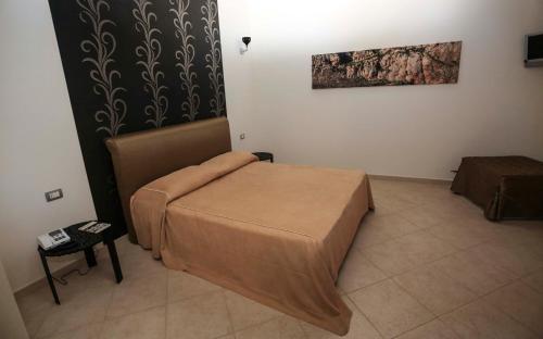 a small bedroom with a bed and a chair at Regalpetra Hotel in Racalmuto