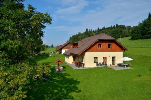 a house on a hill with a green yard at Šumavské apartmány in Zdíkov