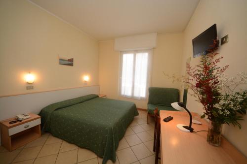 a hotel room with a green bed and a chair at Bike & Family Hotel Derby in Finale Ligure