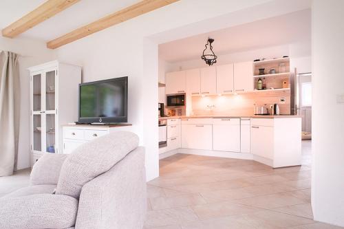 a kitchen with white cabinets and a tv and a couch at Ferienhaus Hillesheim in Hillesheim