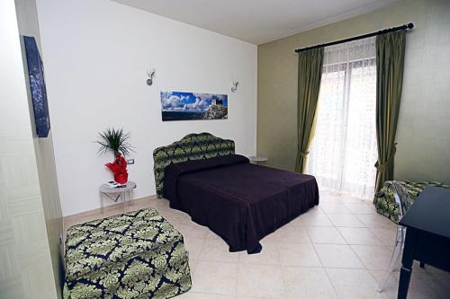 a bedroom with a bed and a chair and a window at Regalpetra Hotel in Racalmuto