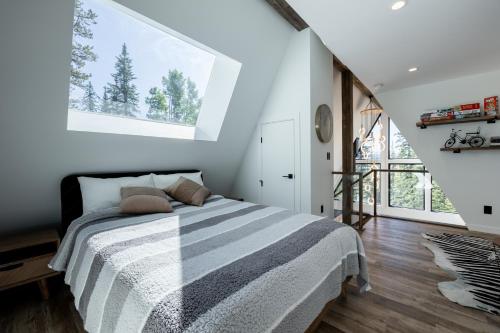 a bedroom with a bed with a large window at New Modern Rustic A-Frame Cabin with Barrel Sauna in Nordegg