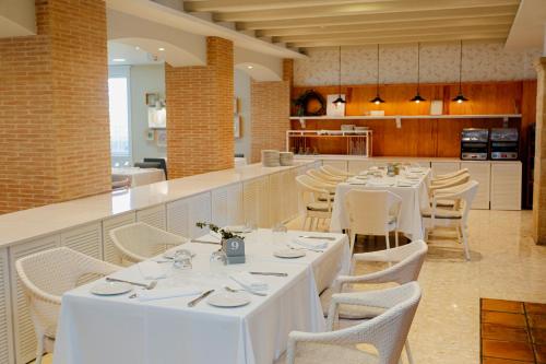 a restaurant with white tables and chairs and a kitchen at Hotel Los Ángeles Denia in Denia