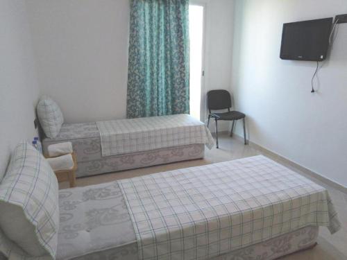 a bedroom with two beds and a flat screen tv at Dar Ziyad Airport in Casablanca