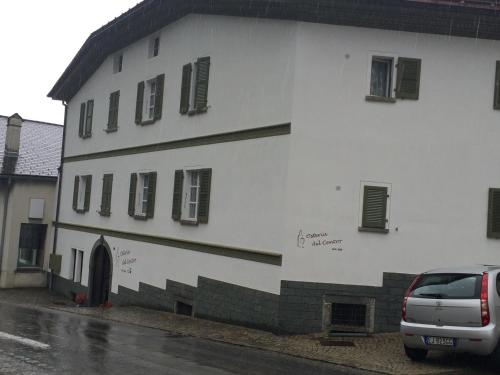 a white building with a car parked in front of it at Osteria Del Centro in Brusio