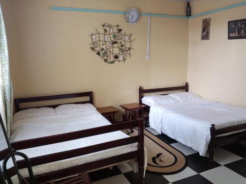 een slaapkamer met 2 bedden en een klok aan de muur bij Quiet Place in Kikuyu