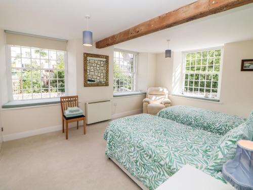 a bedroom with a bed and a chair and windows at Wye Mill in Buxton