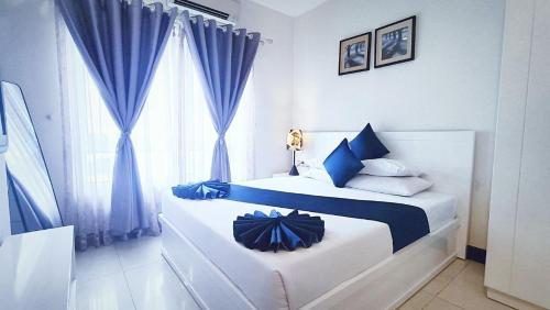a bedroom with a bed with blue curtains and a window at Queen Central Apartment Hotel in Ho Chi Minh City