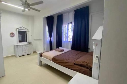 een slaapkamer met een bed met blauwe gordijnen en een spiegel bij Haris Homestay 3 Bedroom and 2 Bathroom in Kota Bharu