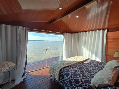 a bedroom with a bed and a large window at SUITE BANGALÔ ILHA Da FANTASIA in Belém