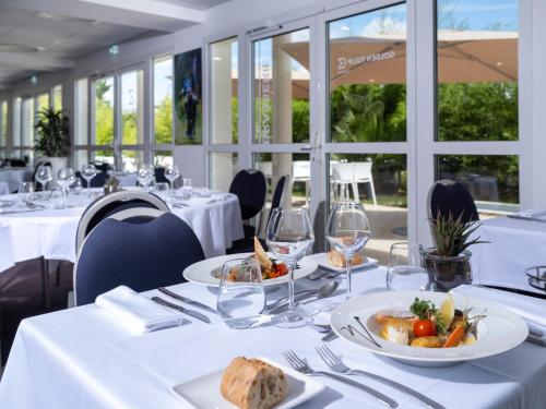 une salle à manger avec des tables blanches et des assiettes de nourriture dans l'établissement Golden Tulip La Baule, à La Baule