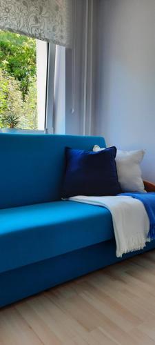 niebieską kanapę w pokoju z oknem w obiekcie Apartament Centrum przy Parku Zdrojowym w Nałęczowie
