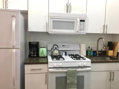 a white kitchen with a stove and a microwave at Cozy Studio Chinatown! Location! in New York