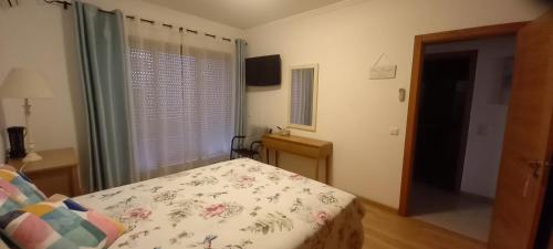 1 dormitorio con cama, ventana y TV en Apartment in the center of Tavira with swimming pool and garage, en Tavira