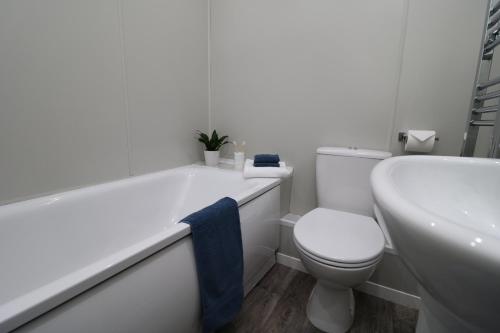 a white bathroom with a toilet and a tub and a sink at Modern 3 Double Bedroom Town Centre Maisonette in Morecambe