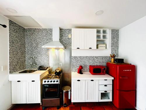cocina con armarios blancos y nevera roja en Viento Azul Guest House, en Punta del Este