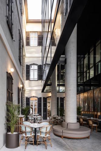 a courtyard with tables and chairs in a building at Elkonin Tel Aviv - MGallery Hotel Collection in Tel Aviv