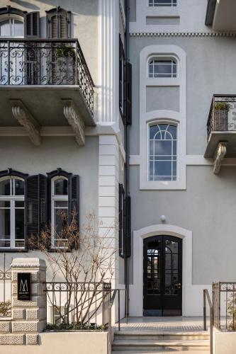 a white building with a black door and a balcony at Elkonin Tel Aviv - MGallery Hotel Collection in Tel Aviv