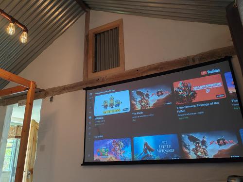 a flat screen tv hanging on a wall at The Bothy near Tenby, Big Projector Screen, Four-poster bed, on-site HOT TUB access via Spa Pack in Tenby