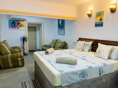 1 dormitorio con 1 cama grande y 2 sillas en Arcadia Resort en Hikkaduwa