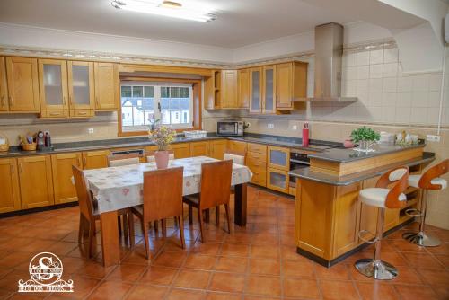 a kitchen with wooden cabinets and a table and chairs at Casa dos sonhos in Chaves