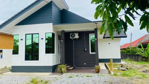 una pequeña casa con un exterior blanco y negro en Kaklah Cherang Homestay en Kota Bharu