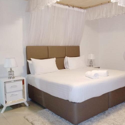 a bedroom with a large bed with white sheets and pillows at Sofitel 3 bedrooms own compound milimani in Kisumu