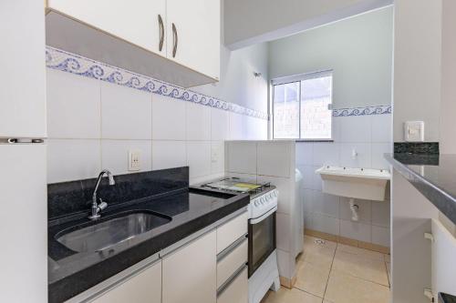 a white kitchen with a sink and a stove at Excelente Apartamento 190m da Praia de bombinhas - 3 dorms 6 pessoas in Bombinhas