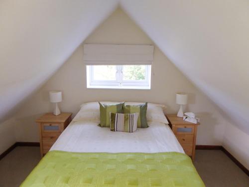 a bedroom with a bed with green pillows and a window at Pump Lodge in Weymouth