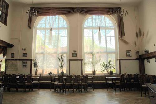 a room with chairs and tables and large windows at Wrzos & Belvedere in Kudowa-Zdrój