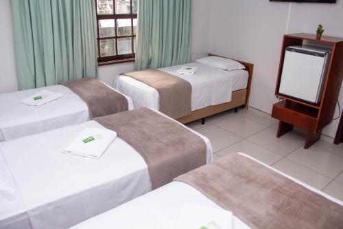 a hotel room with three beds and a television at HOTEL DOMHOF in Blumenau