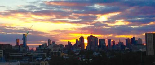 a city skyline with a sunset in the background at Modern Spacious 2BD2Bath - Stunning City Views! in Melbourne