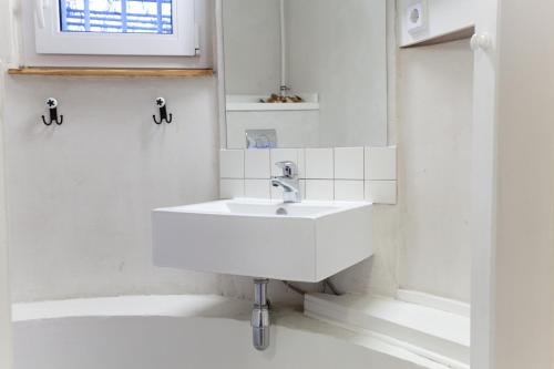 baño blanco con lavabo y ventana en Smart Appart Blücher Berlin, en Berlín