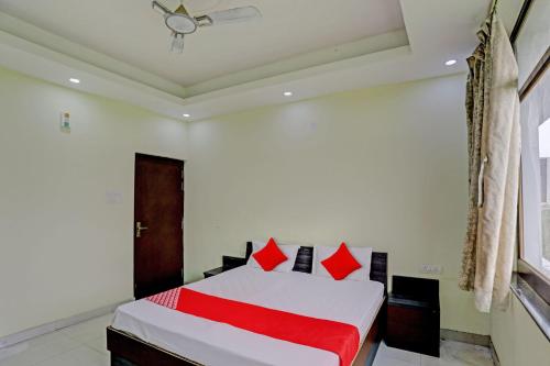 a bedroom with a white bed with red pillows at OYO Flagship Shree Shyam Kripa Hotel And Restaurant in Kānpur