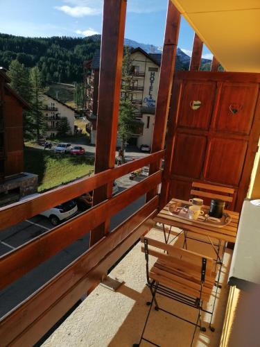 d'un balcon avec un banc et une table offrant une vue. dans l'établissement CŒUR D'ALTAÏR RISOUL 1850 Appartement T2 confortable skis aux pieds, à Risoul