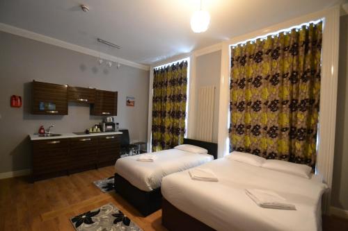 a hotel room with two beds and a kitchen at Hyde Park Suites in London