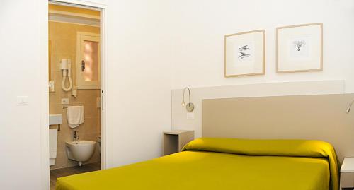 a bedroom with a yellow bed and a bathroom at Hotel Da Mario in Caorle