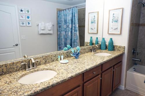 La salle de bains est pourvue de 2 lavabos et d'une douche. dans l'établissement Candy Palm 8885 Water View Townhouse, Sleeps 12, à Kissimmee
