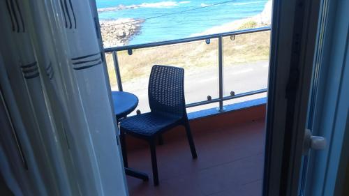 Un balcón con una silla y vistas al océano. en BeiramarApartamento, en Muxía