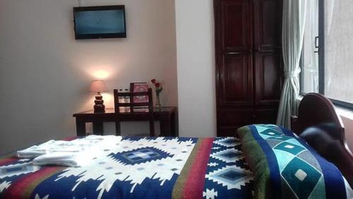 a bedroom with a bed with a quilt on it at Coraza Hotel in Otavalo