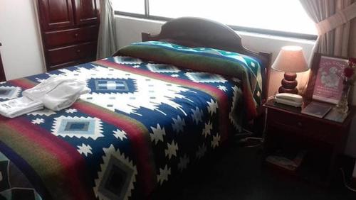 a bedroom with a bed with a colorful blanket at Coraza Hotel in Otavalo
