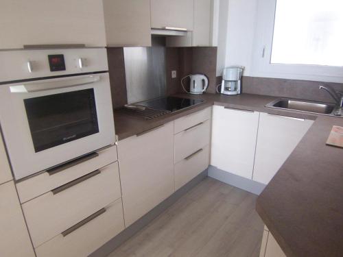 une cuisine avec des armoires blanches et un four à plaques de cuisson dans l'établissement Appartement T3 confortable avec balcon et vue mer, Les Sables-d'Olonne - FR-1-197-169, à Les Sables-dʼOlonne