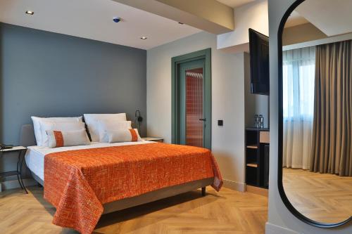 a bedroom with a bed with an orange blanket and a mirror at İn The Middle Hotel in Antalya