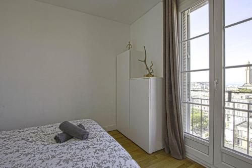 um quarto com uma cama e uma grande janela em F2 immeuble Perret avec vue à 180 ° sur la ville - Parking privatif - Hypercentre em Le Havre
