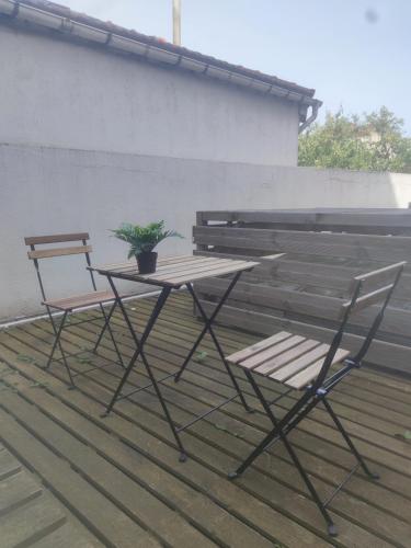 2 sillas y una mesa con una maceta en el patio en Expérience urbaine en Aubervilliers