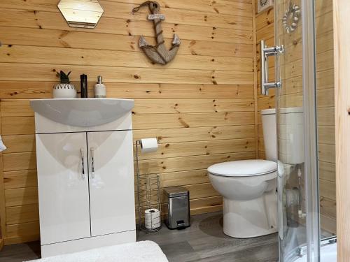 a bathroom with a white toilet and wooden walls at Dwell on the Moor in Holme upon Spalding Moor