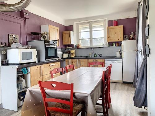 - une cuisine avec des murs violets, une table et des chaises dans l'établissement Villa Près de la Plage, Jardin, Proche Commerces, 4 Ch, Wifi, Idéale Familles - FR-1-361-15, à Jullouville